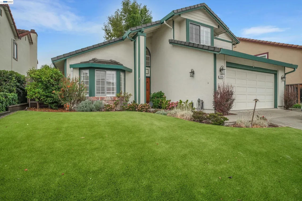 An angled front view highlights the broad lawn, bay window, and attached two-car garage at 19475 Mount Jasper Drive.